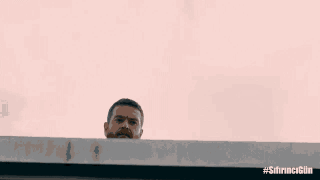 a man with a beard is looking over a ledge with the hashtag #sihrncgun