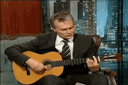 a man in a suit is playing a guitar