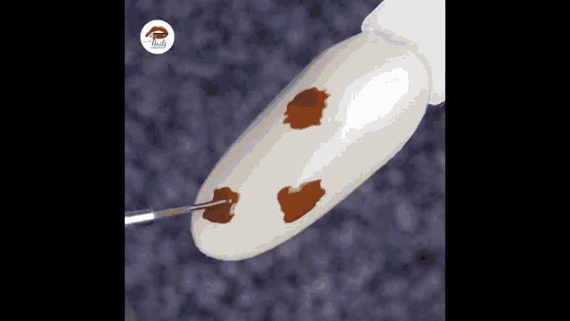 a close up of a nail being painted with brown paint