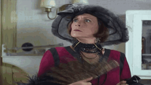 a woman is wearing a hat and holding a fan in her hand