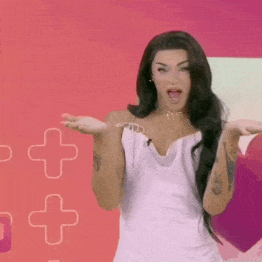 a woman in a white dress is standing in front of a pink background with hearts and crosses .