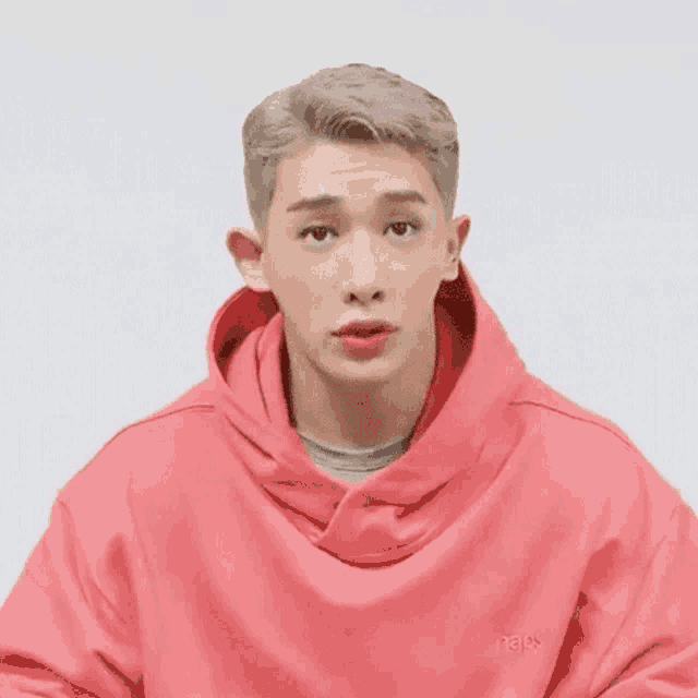 a close up of a man wearing a red hoodie making a funny face .