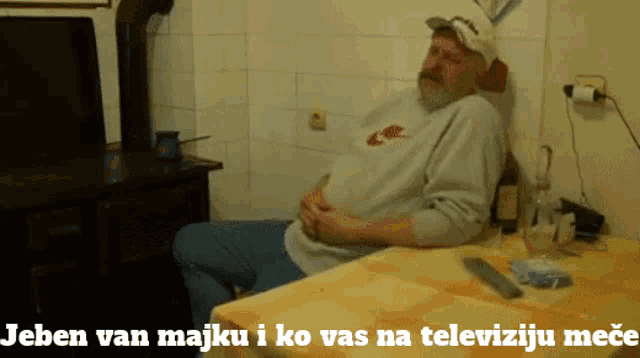 a man is sitting at a table with the words jeben van majku i ko vas na televiziju mece
