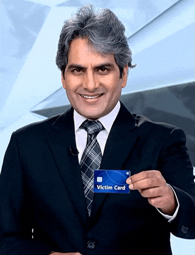 a man in a suit and tie holding a victim card
