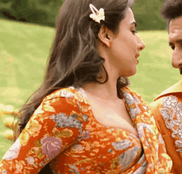 a woman with a flower in her hair is standing next to a man in a field .