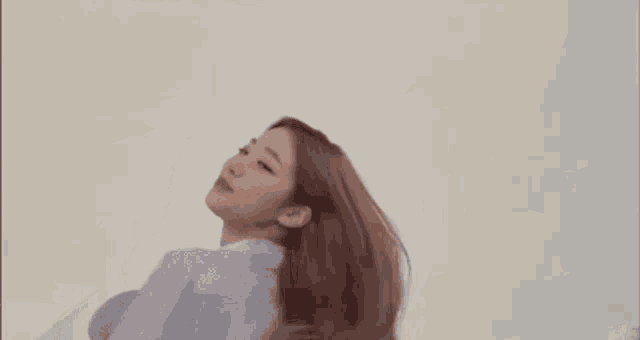 a woman with long brown hair is standing in front of a white wall .