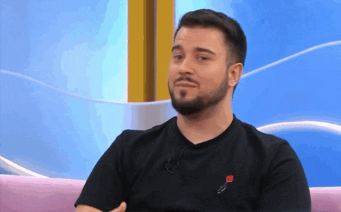 a man with a beard is wearing a black t-shirt with a rose on it .