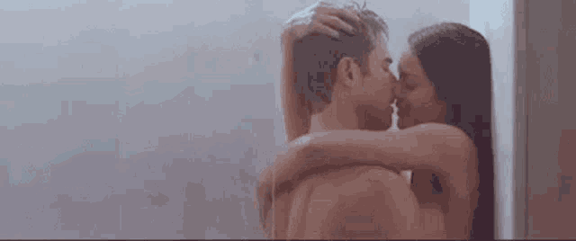 a man and a woman kissing in a shower .