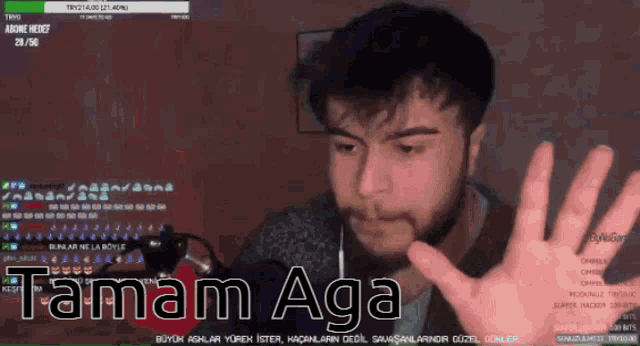a man in front of a microphone with the words tamam aga on the screen