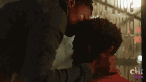 two men are kissing in front of a sign that says " the chi "