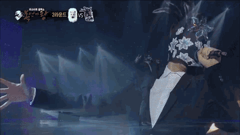 a man in a suit is performing on a stage with a mask on