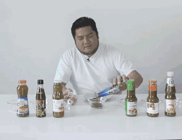 a man is pouring a bottle of sauce into a glass bowl