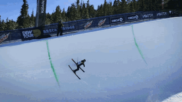 a person is skiing down a snow covered slope with toyota and dew tour banners in the background