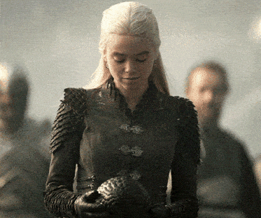 a woman in a black jacket holds a dragon egg in her hands