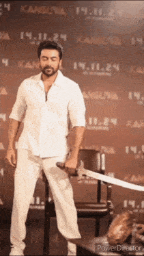 a man in a white shirt is holding a sword in front of a sign that says kanguna