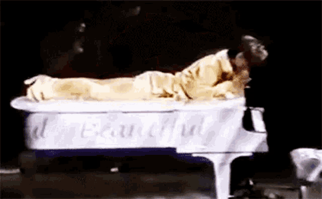 a man is laying on top of a white grand piano .