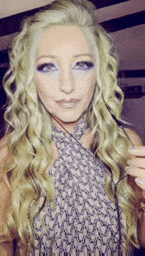 a woman with blonde hair and blue eyeshadow is wearing a halter top