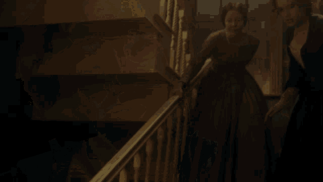 a woman in a green dress is walking down a staircase
