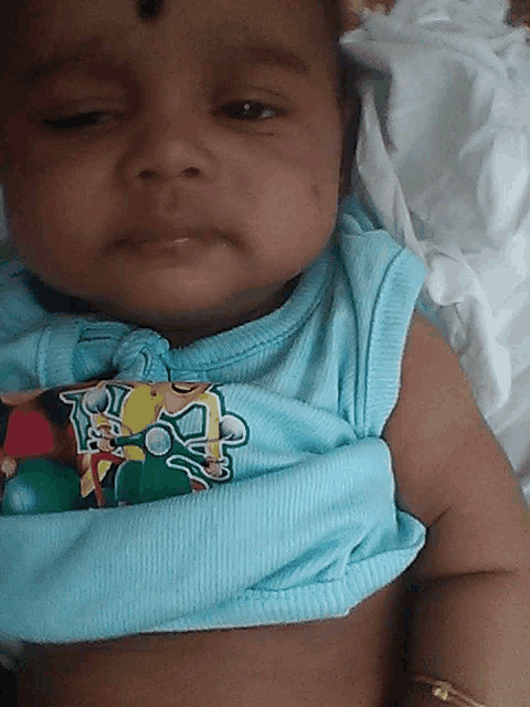 a baby wearing a blue shirt with a picture of a cartoon character on it