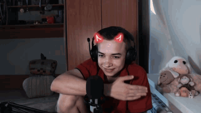 a young man wearing headphones with devil horns on his head looks at the camera