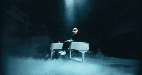a person sitting on a white piano with smoke coming out of it