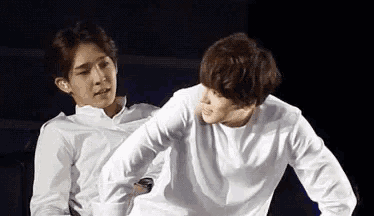 two men in white shirts are sitting next to each other on a black background .