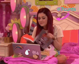 a girl is reading a book while using a laptop with a sticker that says ' a7cunt ' on it