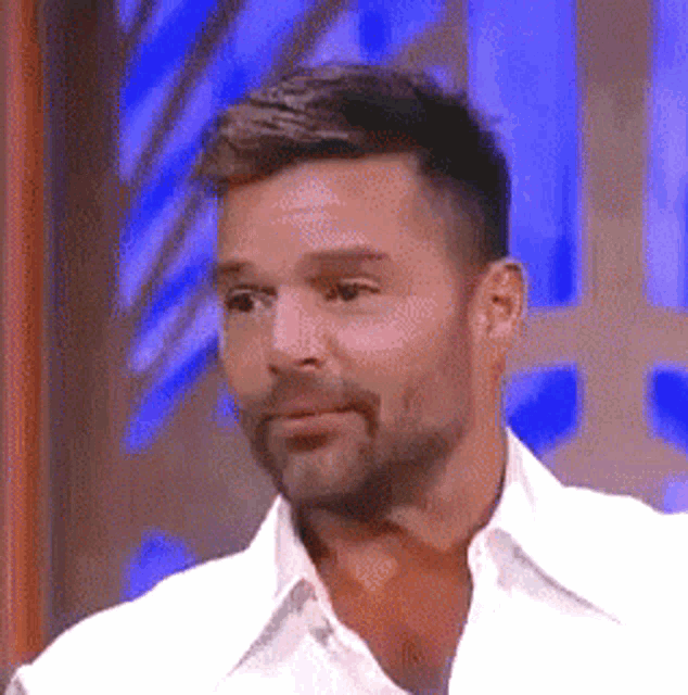 a man with a beard wearing a white shirt is making a funny face .