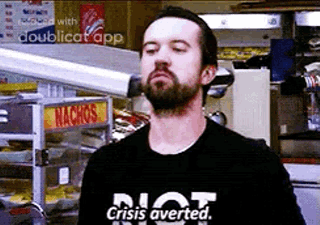 a man with a beard is wearing a t-shirt that says `` not crisis averted . ''