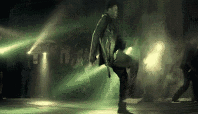 a man is dancing on a stage in a dark room with green lights .