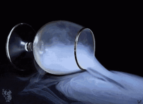 smoke is coming out of a wine glass on a table