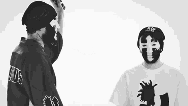 a man wearing a shirt that says " kills " stands next to another man