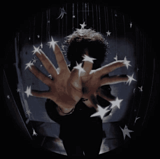 a man 's hands are reaching out towards a ceiling with stars hanging from it .