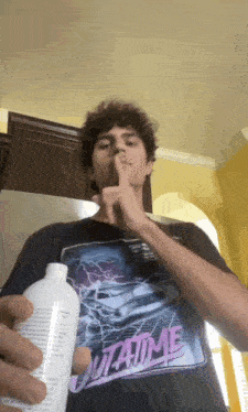 a young man wearing a shirt that says outatime is holding a bottle