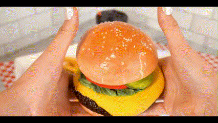 a person is holding a hamburger in their hands and eating it .