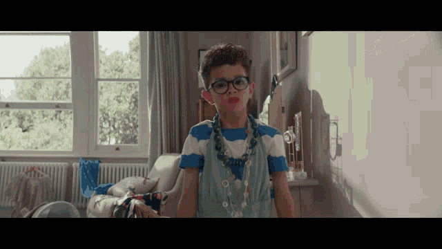 a young boy wearing glasses and a necklace with red lipstick on his lips