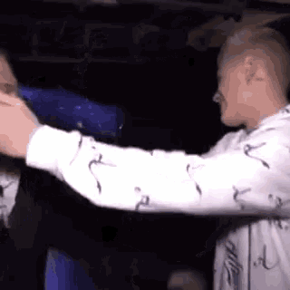 two men are standing next to each other in a dark room .