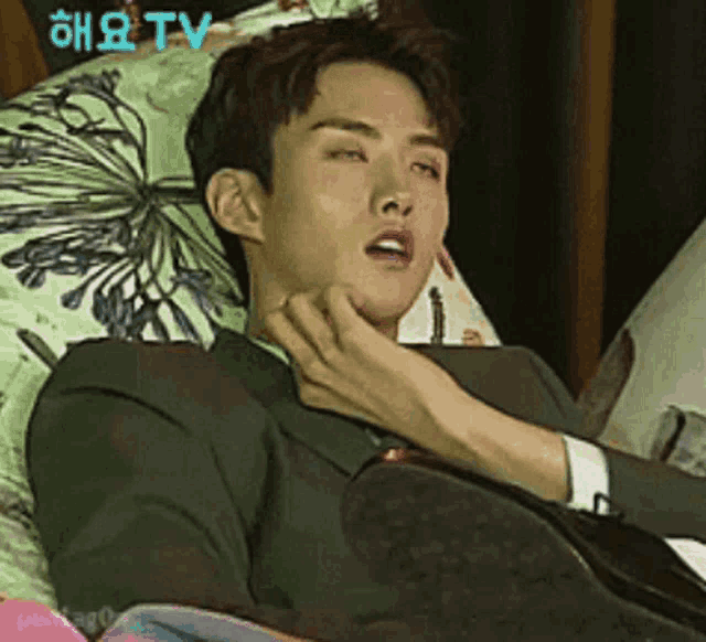 a man in a suit is laying on a bed with a pillow that says tv