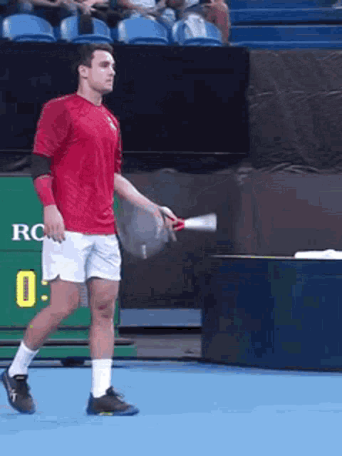 a man in a red shirt and white shorts is holding a tennis racquet on a tennis court ..