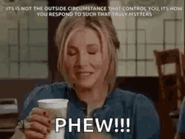 a woman is sitting at a table holding a cup of coffee and saying phew !