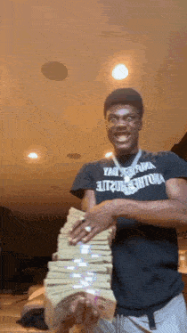 a man in a black shirt is holding a pile of money .