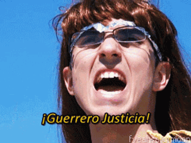 a woman wearing sunglasses and a wig shouts guerrero justicia in spanish