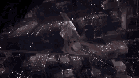 an aerial view of a woman in a white dress flying over a city at night .
