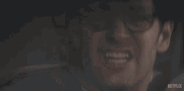 a man with glasses is smiling in a dark room with netflix written on the bottom