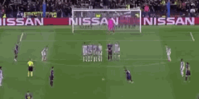 a soccer game is being played in front of an ad for nissan .