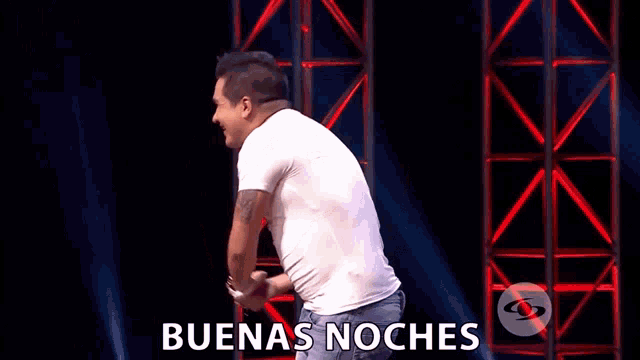 a man in a superman shirt is standing on a stage with the words buenas noches behind him
