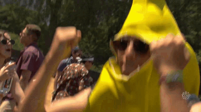 a man wearing a yellow banana costume is dancing in a crowd at a music festival