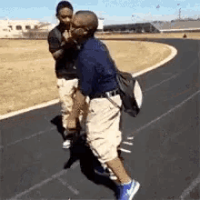 two men are standing next to each other on a track . one of the men is carrying a backpack .
