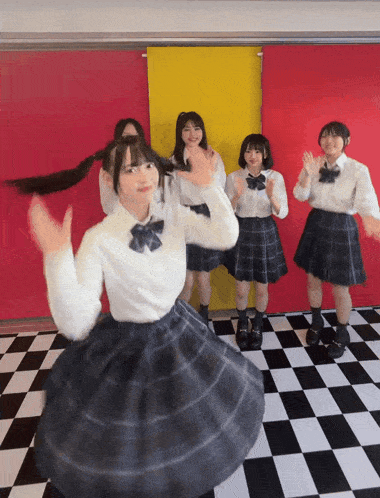 a group of girls in school uniforms are dancing on a checkerboard floor