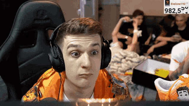 a man wearing headphones is sitting in front of a screen that says 982.5